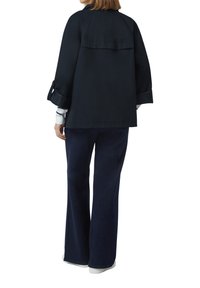 Marineblauwe utilityjack met een losse pasvorm, voorzien van brede mouwen, een rugpand en een flapzakdetail. Gecombineerd met donkere denimbroek.