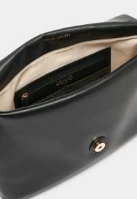 Borsa in pelle nera con una texture liscia, dotata di un dettaglio in metallo dorato e un interno in tessuto beige con più tasche.