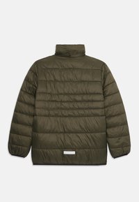 Veste matelassée vert foncé avec des coutures horizontales, col montant, poignets élastiques et un petit patch réfléchissant rectangulaire près de l'ourlet.