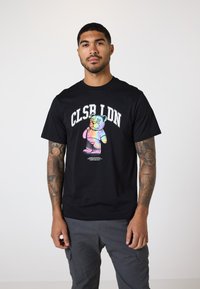 Sort bomulds t-shirt med et farverigt bjørnegrafik og "CLSR LDN" tekst ovenfor. Rund halsudskæring og korte ærmer. Casual pasform.