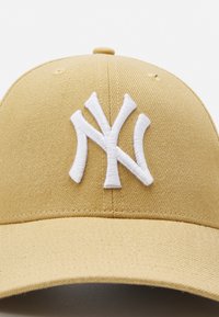 Gorra amarilla de tela con una superficie texturizada, que presenta un prominente logotipo bordado en blanco con las letras "NY" en la parte frontal.