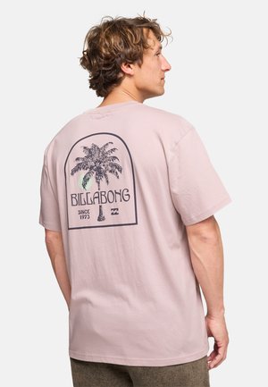 T-shirt en coton rose clair avec un motif de palmier noir et du texte à l'arrière, coupe décontractée et manches courtes.