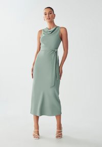 Cowl-neck, sleeveless dress in light green fabric, midi length, with a tied waist detail. Smooth texture and subtle draping.
