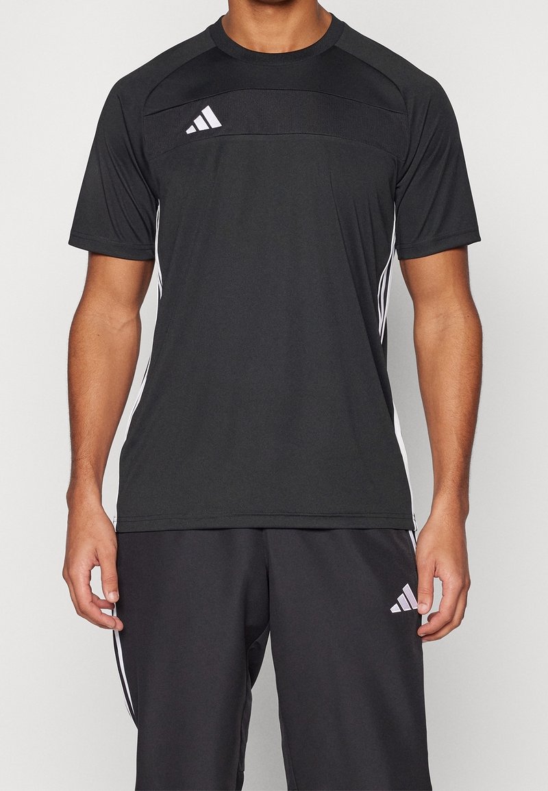 Svart idrottströja med korta ärmar, kontrasterande vita adidas-ränder på sidorna och en strukturerad panel på bröstet.