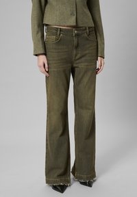 Oliivroheline laiade jalgadega teksased, räbalate servadega, teksakanga tekstuur, viie taskuga disain ja õrnad fade'in' detailid.