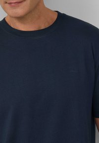 T-shirt in cotone blu navy con colletto girocollo classico, maniche corte e un sottile logo s.Oliver sul lato sinistro del petto. Texture morbida.