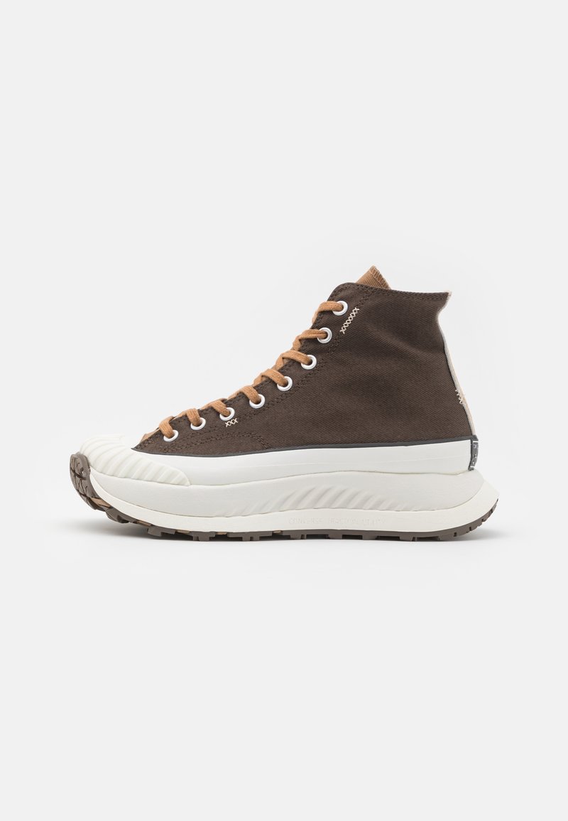 Baskets montantes avec dessus en tissu marron, lacets beige, semelle blanche épaisse et embout blanc texturé, vues de côté sur fond blanc.