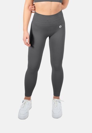 Gray high-waisted leggings made of stretchy material, featuring a ribbed texture and a small logo accent on the thigh, worn with white sneakers.