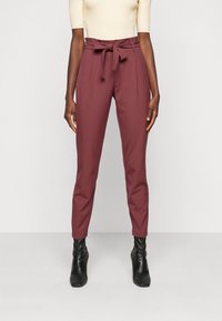 Vínové kalhoty na míru s vysokým pasem a zavazováním v pase. Mají ostré skladby a zúžené nohavice. Nosí se s černými kotníkovými botami.