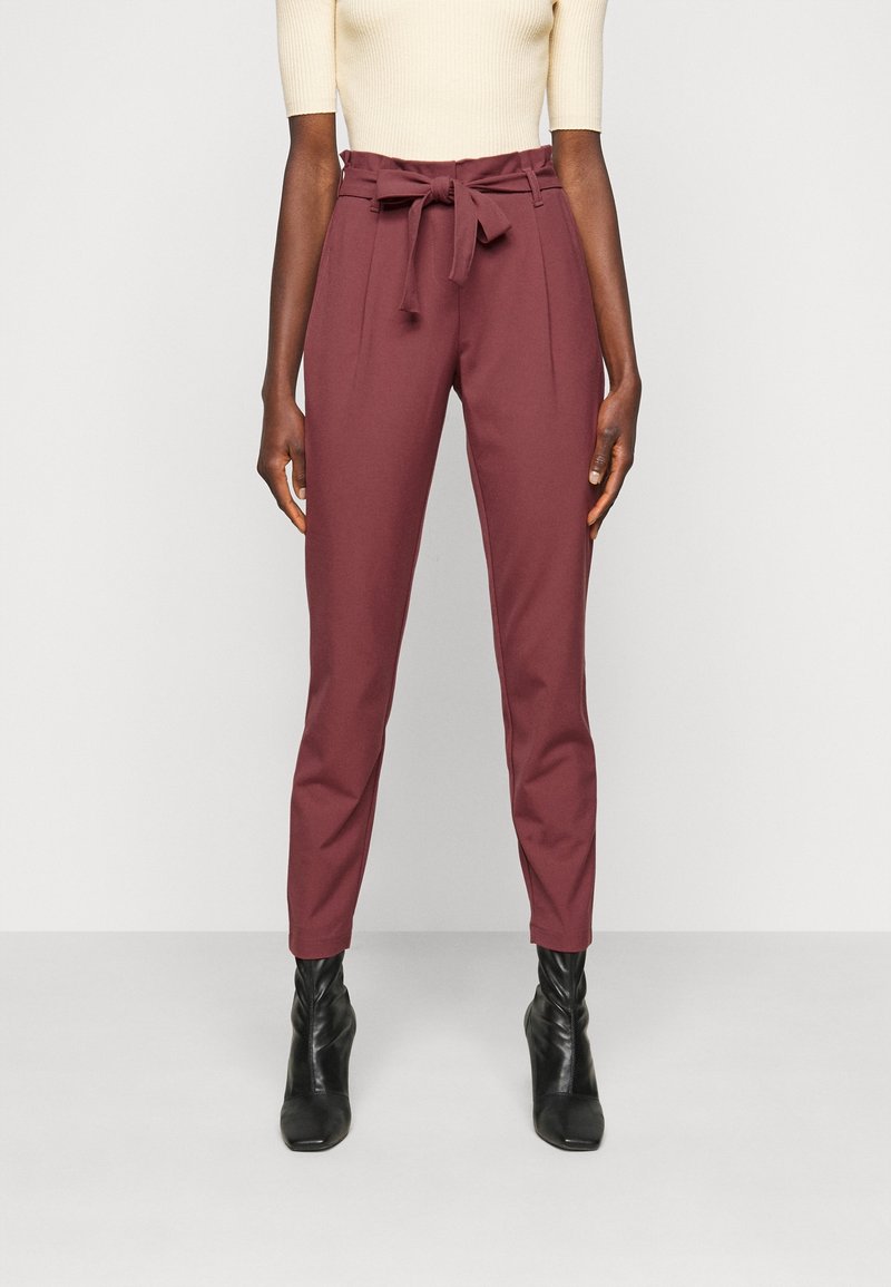 Vínové kalhoty na míru s vysokým pasem a zavazováním v pase. Mají ostré skladby a zúžené nohavice. Nosí se s černými kotníkovými botami.