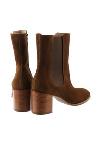 Bruna mockaläder ankelboots med rundad tå, elastiska sidopaneler och en medelhög träklack. Slät yta utan synlig hårdvara.