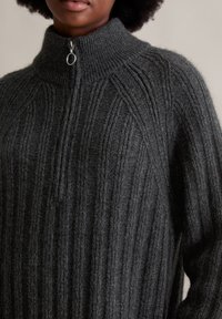 Charcoalkleurige gebreide trui met een hoge kraag, voorzien van een ribbelstructuur en een ritsluiting bij de hals. Zacht en dik materiaal.