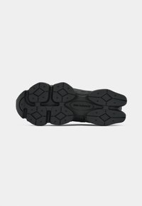 Semelle de chaussure de sport noire avec un motif de grip texturé, ornée d'accents en forme de diamant et de la marque emblématique "New Balance".
