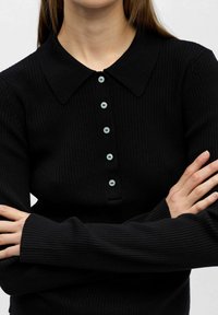 Sort ribbestrikket langermet genser med krage og fem lyseblå knapper foran. Tettsittende design med forlengede mansjetter.