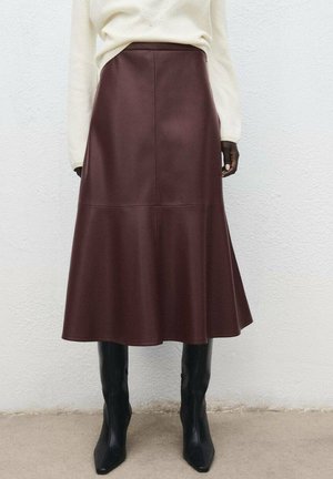 Jupe midi en cuir marron avec un ourlet évasé, dotée de panneaux sans couture et arrivant au-dessus du genou. Assortie à des bottes noires jusqu'aux genoux.