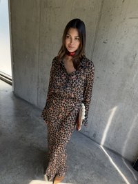 Sukienka w panterkę z długim rękawem w odcieniach brązu i czerni, o swobodnym kroju, zestawiona z małą brązową torebką z teksturowymi akcentami.