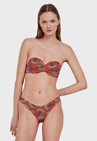 Crveni bikini set koji uključuje top bez naramenica s uvijenim dizajnom i uzorkom lepeze, uparen s pripadajućim donjim dijelom niskog struka u istom uzorku.