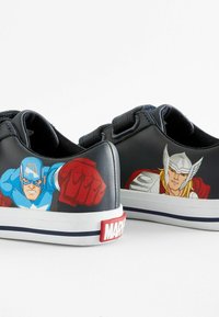Sneakers neri con grafiche di Captain America e Thor su ciascun lato. Suole in gomma, accenti rossi e dettagli blu e bianchi sul tallone.