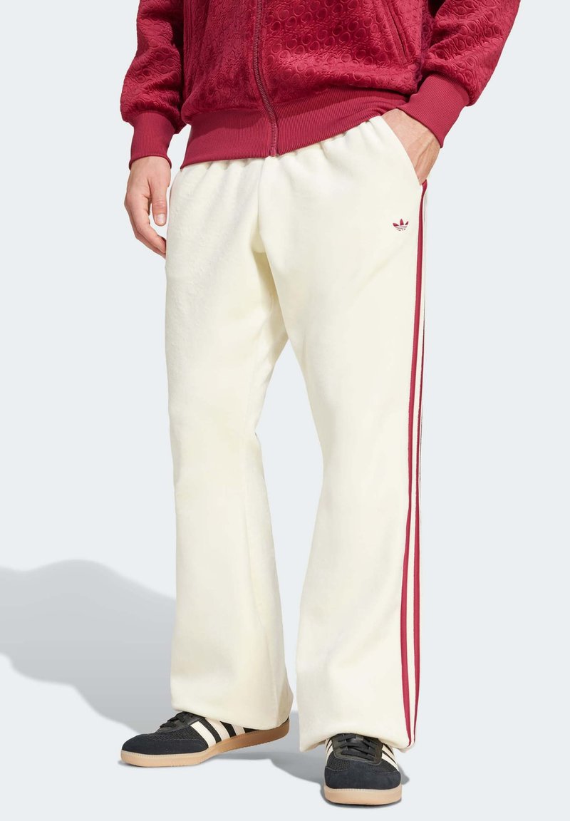 Kremfargede fleece joggebukser med røde sidekanter, med en avslappet passform og en brodert logo på lommen.