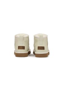 Botas de tobillo de cuero texturizado blanco con forro de piel de oveja suave, suela de goma marrón y etiqueta de marca marrón en la parte trasera.
