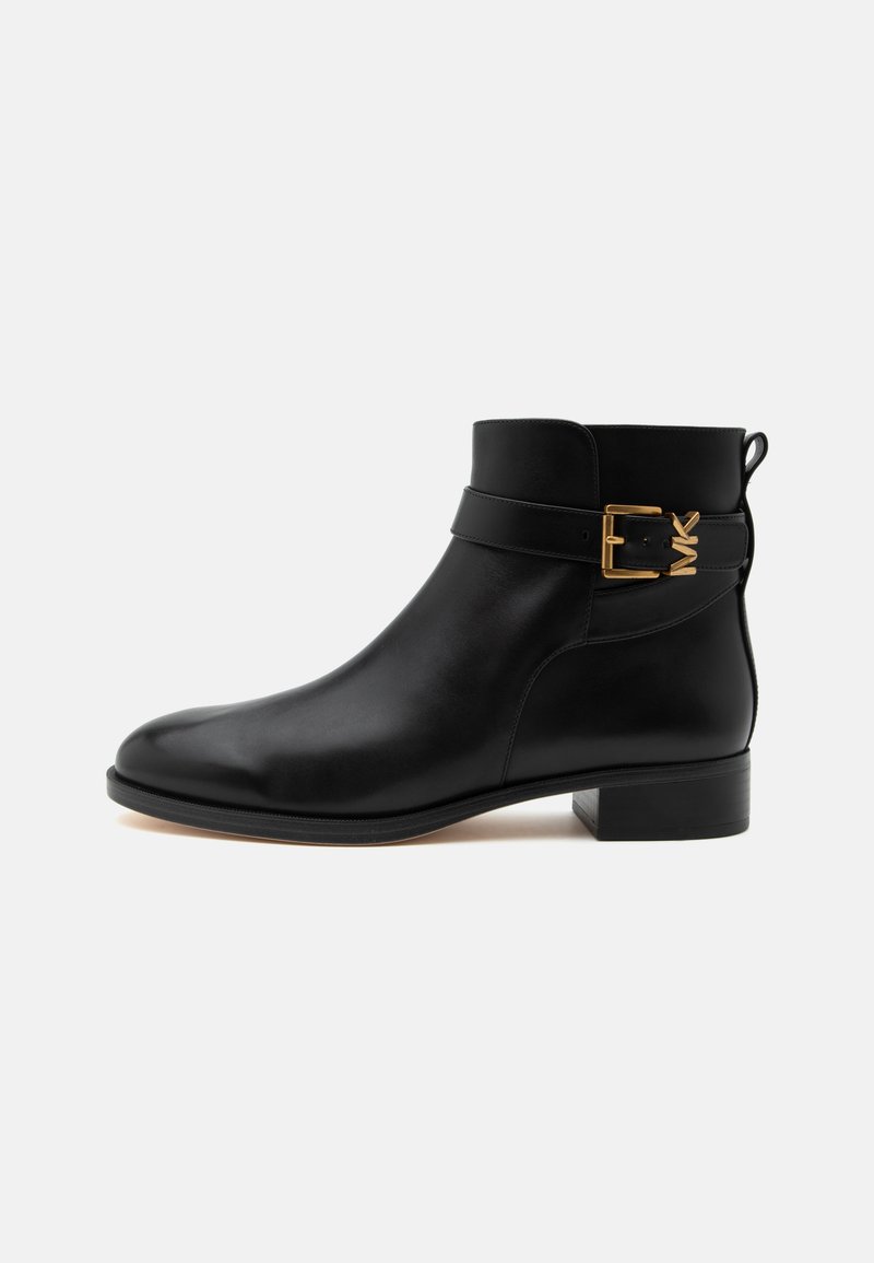 Bottine en cuir noir avec petit talon et détail de sangle à boucle dorée sur le côté sur fond blanc.
