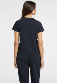 Navy blue cotton t-shirt with short sleeves, round neckline, and a relaxed fit. Features a smooth texture and standard cut at the waist.