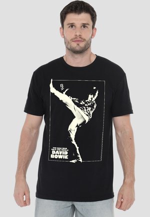 Black cotton t-shirt featuring a white graphic print of a person kicking, with the text "THE MAN WHO SOLD THE WORLD DAVID BOWIE" below.
