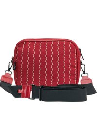 Červená krosbody taška s vlnitým bílým vzorem, zipovým uzávěrem, černým nastavitelným popruhem a kontrastními červenými akcenty na popruzích a kování.