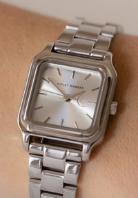 Silver stainless steel watch with a square face, textured silver dial, and stick markers. Features a polished bracelet and logo "VIOLET HAMDEN."