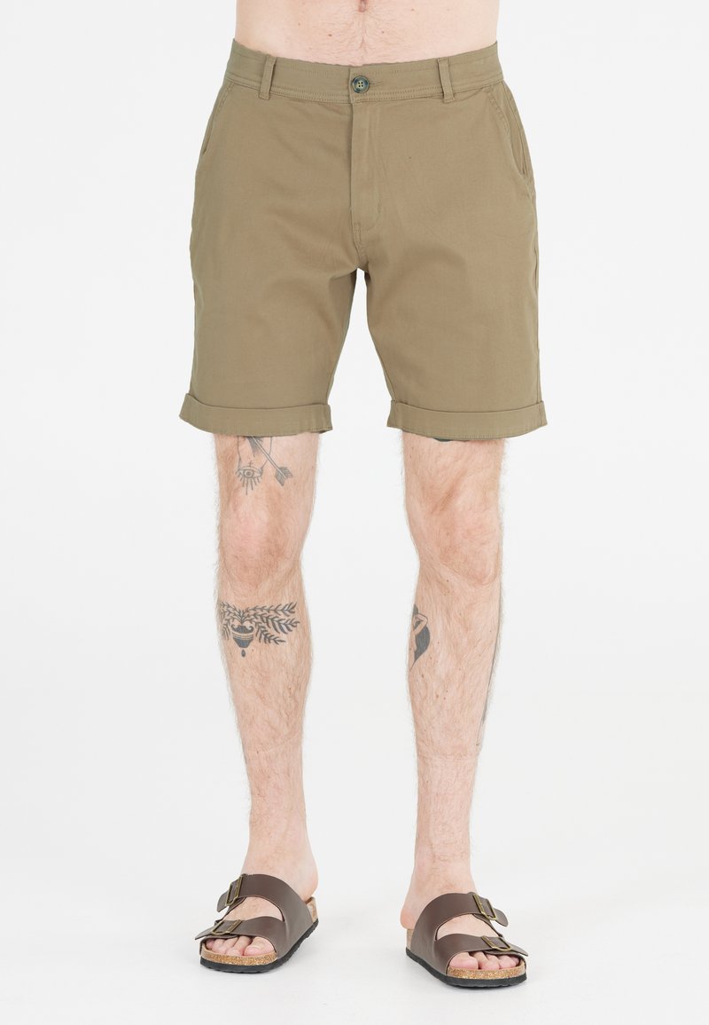 Kakifärgade shorts i bomullsblandning, med flat front, uppvikt fåll, sidofickor och en knappstängning. Bärs med bruna sandaler.