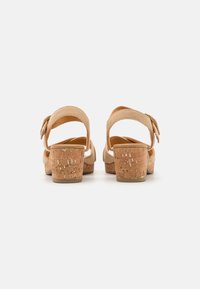 Beige sandalen met kurk hak, verstelbare band en textuur bovenkant. Een eenvoudig ontwerp met een ronde vorm en een lichte, natuurlijke afwerking.