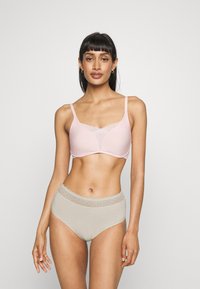 Light pink wireless bra with a mesh panel and flat straps paired with high-waisted, beige briefs featuring a lace trim. Smooth texture.