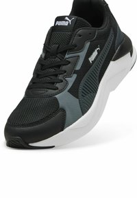 Scarpa da atletica nera e grigia con tomaia in rete, sovrapposizioni sintetiche e suola bianca. Presenta lacci, collo imbottito e logo Puma sulla linguetta.