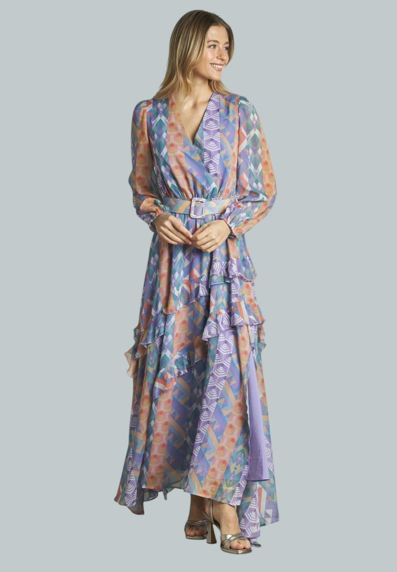 Langes, fließendes Kleid in helllila mit bunten geometrischen Mustern. Mit Rüschen, einem gebundenen Gürtel und langen Ärmeln; leichtes Material.