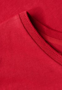 Röd bomulls-t-shirt med rund hals som har en ribbad krage och slät textur, vikt snyggt. Inga synliga mönster eller detaljer.