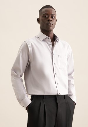 Lichtgrijze overhemd met lange mouwen, knoopsluiting, één borstzak en een patroon aan de binnenkant van de kraag, gecombineerd met zwarte broek.