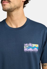 Navyblauwe katoenen t-shirt met een grafisch zakontwerp van palmbomen, bergen, een zon en de tekst "RVCA" in pastelkleuren.