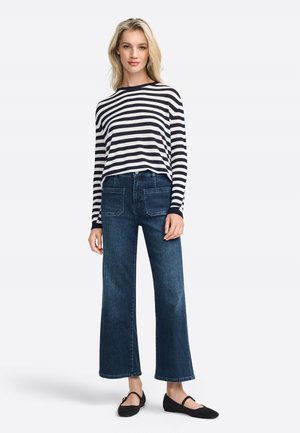 Maglietta a maniche lunghe a righe in blu marino e bianco, abbinata a jeans larghi blu. Presenta un collo rotondo e ballerine nere piatte.