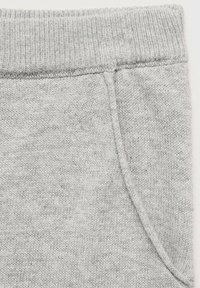 Siva pletenina s rebrastim elastičnim pasom in stransko žepom. Tekstura je mehka in gladka z rahlo melange vzorcem.