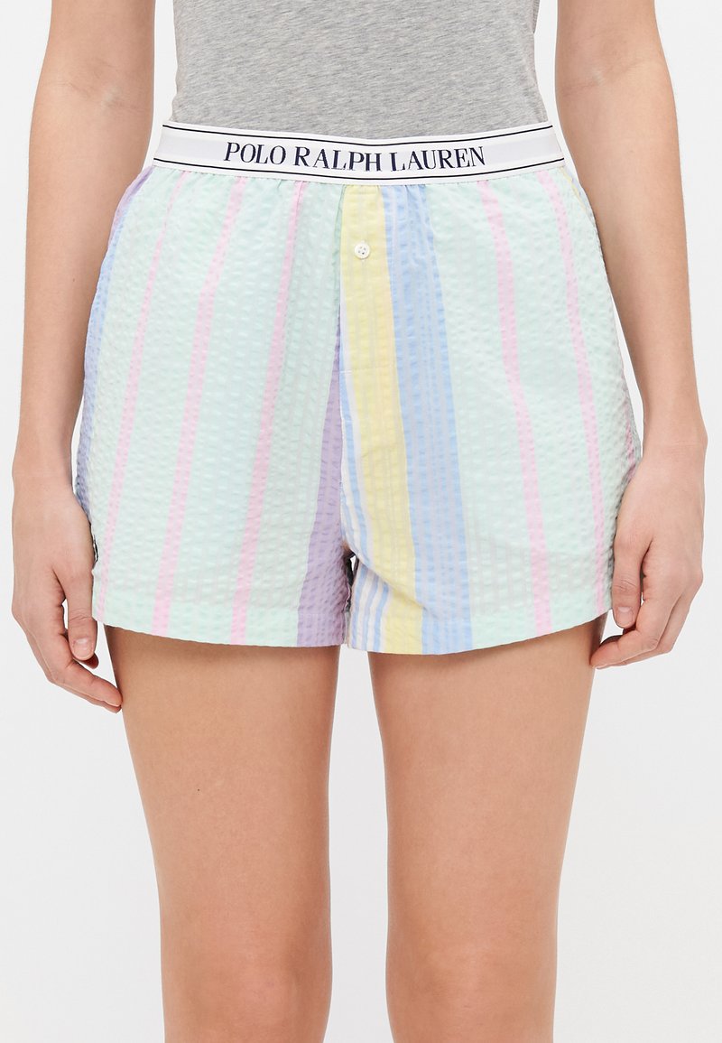 Kort broek met wafeltextuur en pastelkleurige strepen, voorzien van een elastische tailleband met merk en een knoopsluiting aan de voorkant. Kleuren zijn roze, geel en blauw.