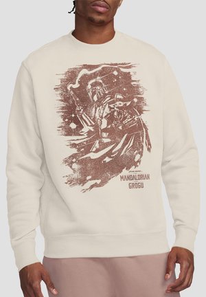 Beigefarbener Sweatshirt mit einem abgenutzten Bild von The Mandalorian, der einen Blaster hält, mit Grogu vor einem Weltraum-Hintergrund.