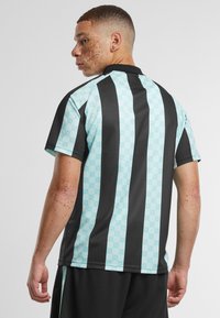 Korte mouwen trui met afwisselend zwarte en lichtblauwe verticale strepen, met een subtiel patroon op de blauwe gedeelten en een zwarte kraag.