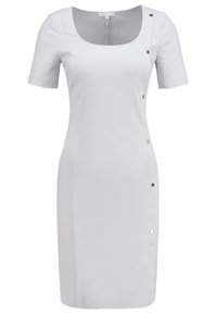 Robe blanche longueur genou avec manches courtes, encolure dégagée et boutons décoratifs disposés verticalement le long du côté droit.