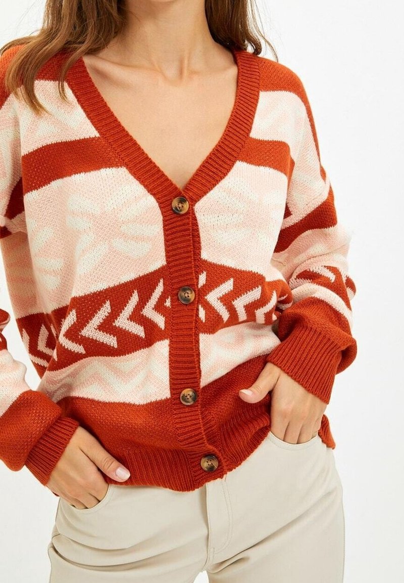 Gestrickte Strickjacke in Rost und Creme mit V-Ausschnitt, geometrischen Mustern, fünf braunen Knöpfen sowie gerippten Bündchen und Saum.