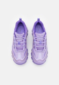 Ett par kraftiga lavendelfärgade Skechers-sneakers med texturerade och släta paneler, tjocka sulor och snörningsdetalj, visade uppifrån.