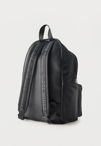 Μαύρο σακίδιο με ρυθμιζόμενους επενδυμένους ιμάντες ώμου με διακριτικό κείμενο, λαβή μεταφοράς στην κορυφή και πλαϊνή τσέπη με φερμουάρ.