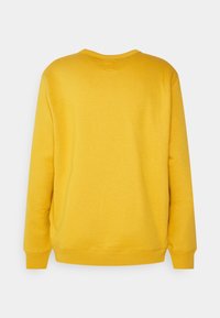 Sudadera de algodón amarilla con mangas largas, cuello redondo y puños de canalé. Textura suave con un color sólido y sin patrones ni acentos visibles.
