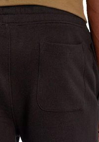 Pantaloni della tuta neri realizzati in tessuto morbido, con una sola tasca posteriore e una vita elasticizzata per comfort e facilità d'uso.