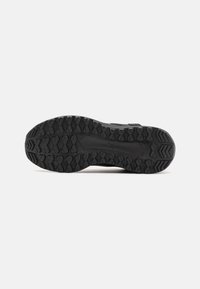 Suela de zapato deportivo negro con un patrón de agarre texturizado, material de goma resistente y un diseño de perfil bajo para tracción y estabilidad.