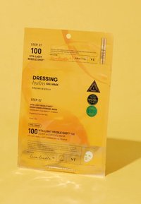 Hydrogelmaskens förpackning i en glansig, ljusgul färg, med svart text som beskriver produktsteg och fördelar, tillsammans med produktbilder och symboler.